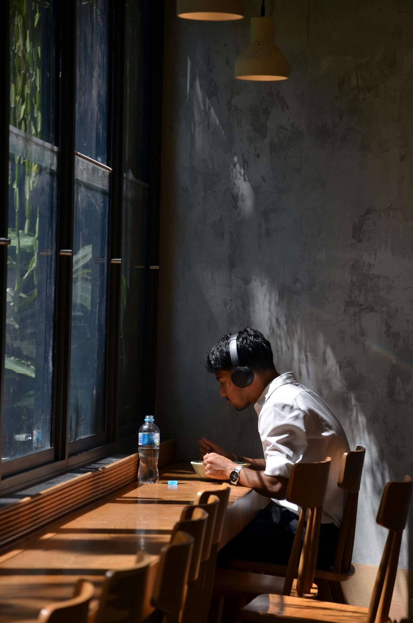 Student with headphones eating at a sunlit cafe counter