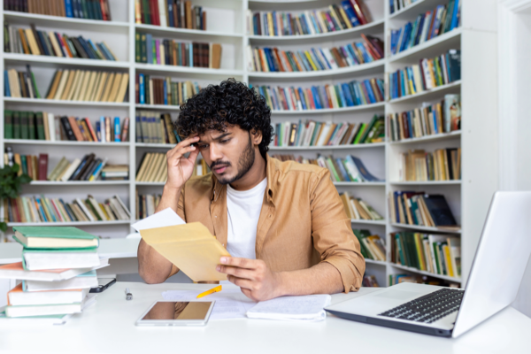 Student studying at a desk looking stressed